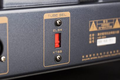 Nærbillede fra siden af Cayin HA-6A hovedtelefonforstærkerens sorte metalkabinet, der viser den røde EL34/KT88 rørvælger indrammet af en gylden kant og fastgjort med to skruer