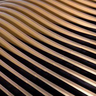 Artnovion Avalon Flow II dekorativt akustisk panel i vekslende bølgede striber af lyst træ og sort stof