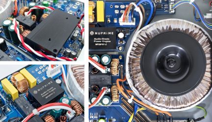 Detailní záběr elektronických součástek na modré desce, měděné cívky, červené a bílé kabely, kruhový transformátor
