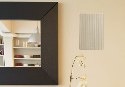 Muro beige con grande specchio a cornice in legno scuro, piccolo pannello rettangolare a strisce chiare, stelo di orchidea bianca