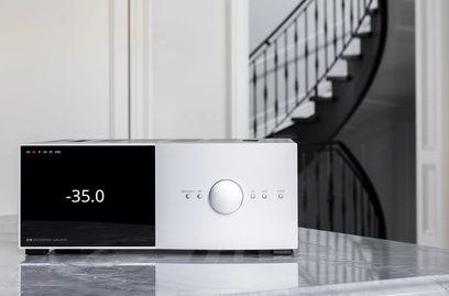 Anthem STR geïntegreerde zilveren stereo hi-fi versterker, vooraanzicht, display "-35.0", geplaatst op reflecterend oppervlak, trap op de achtergrond