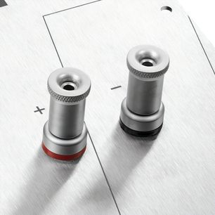 To sylindriske metalltupper med et rødt bånd ved basen, på en hvit teksturert overflate
