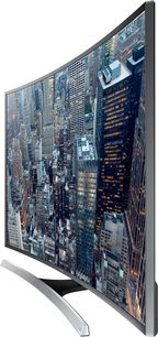 Buet Samsung UE65JU7500-tv der viser et natligt luftfoto af en tætbefolket by med oplyste bygninger