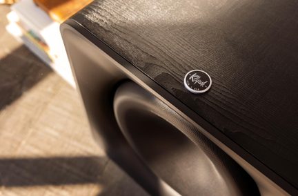 Subwoofer Klipsch negru, carcasă din lemn texturat, vedere de sus cu emblemă rotundă argintie