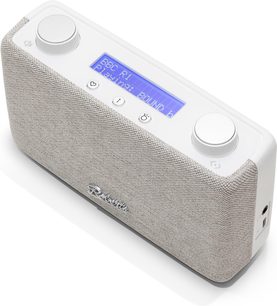Radio de sobremesa Roberts Play 11 color crema, vista en tres cuartos desde arriba, carcasa de plástico liso con frontal de tela texturizada beige, pantalla LCD retroiluminada en azul incrustada en la parte superior entre dos grandes ruedas plateadas y tres pequeños botones.
