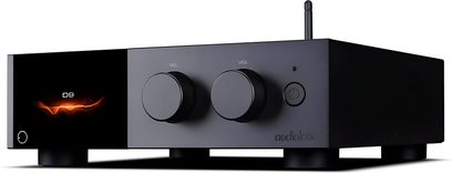 Audiolab D9 svart DAC-ljudomvandlare, metallhölje med frontpanel i både blankt och matt utförande, två stora rattar på framsidan, strömknapp och LED, liten orange grafisk display till vänster, synlig antenn på baksidan, placerad på cylindriska fötter, trekvarts vy framifrån