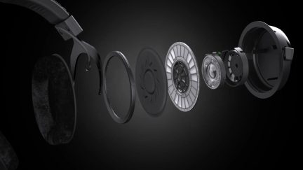Exploded side view of a headphone earcup, black plastic and silver metal parts, foam earpad, transducer