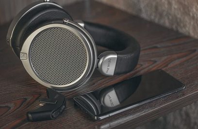 Gesloten Hifiman Deva Pro over-ear hoofdtelefoon, zwart en zilver, met grote drivers, liggend op een donkere houten ondergrond