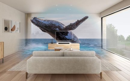 Vista frontal de una sala de estar con sofá beige, mesa de centro redonda, mueble de TV de madera clara, pantalla plana, pared con imagen de ballena.