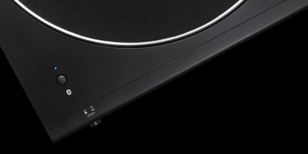 Sort vinylpladespiller med rundt tallerken, Bluetooth-knap og hastighedsvælger 33/45 set i detaljer fra en vinkel