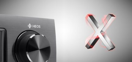 Sort drejeknap "HEOS" og sølvfarvet metallisk "X"-formet logo på lys grå baggrund