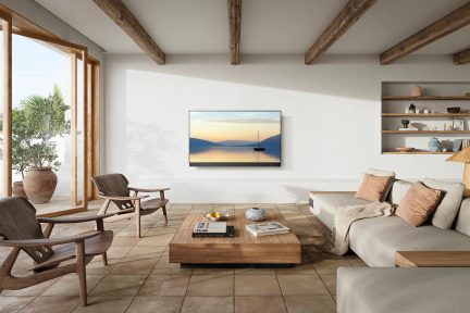 Sala con sofá esquinero gris, 2 sillones de madera, mesa de centro de madera, televisión de pared, estantes de pared, grandes ventanas