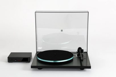 Platine de vinil hi-fi Rega Planar 3 RS com base retangular preta, prato circular transparente, braço de leitura preto, tampa transparente levantada, caixa de controle retangular preta com botões e visor vermelho.