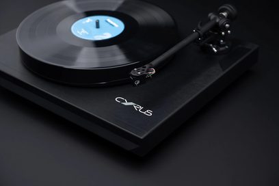 Siyah Cyrus TTP hi-fi vinil plak çalar, üstten yakın çekim görüntü. Mat siyah plak tablası, merkezde mavi etiket. Siyah tonkol ve kapsül