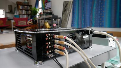 AudioValve Assistent 50 black stereo hi-fi amplifier, front view, 4 tubes, 4 red knobs, RCA jacks at the rear, cables connected