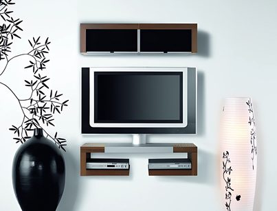 Vægmonteret TV-møbel i træ med to hylder og en drejelig sort TV-holder i midten, under en fladskærm, med en lampe og en vase