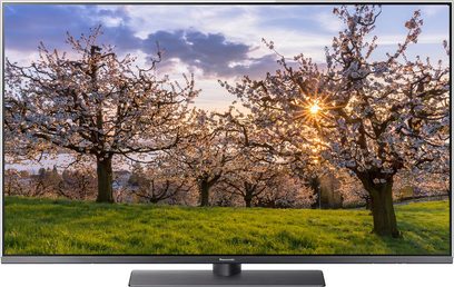 Panasonic TX-65FX780 fladskærms-TV, der viser et fotografi af kirsebærtræer i blomst ved solnedgang
