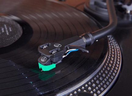 Celulă phono Audio-Technica neagră cu vârf verde pe braț de pick-up pentru DJ, vedere de aproape
