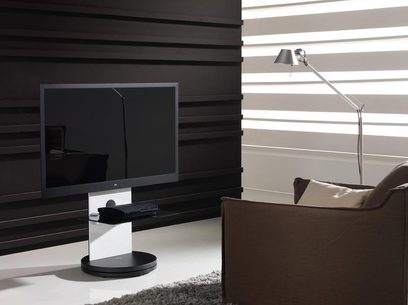 Czarna i biała szafka na telewizor, płaski ekran, chromowana przegubowa lampa biurkowa, ściana z poziomymi białymi i szarymi pasami