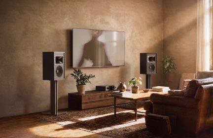 Coppia di diffusori hi-fi neri su supporti ai lati di un televisore a parete in un accogliente soggiorno
