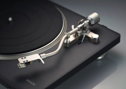 Черен грамофон Denon със сребристо S-образно рамо и противотежест, близък план отгоре
