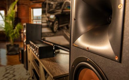 Enceinte acoustique noire avec logo Kingsaudio, vue rapprochée de côté dans un intérieur en bois