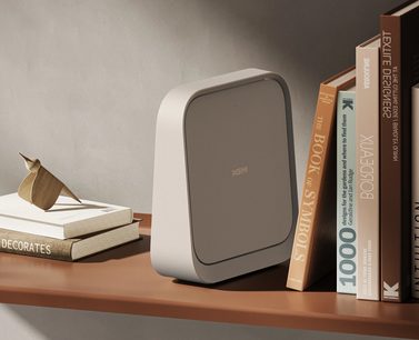 XGIMI Elfin Flip beamer, afgeronde rechthoekige vorm, lichte kleur, geplaatst op een plank met boeken en houten sculptuur