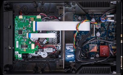 Indvendig i en åben Cyrus CDi-XR CD-afspiller, set ovenfra, med synlige elektroniske og mekaniske komponenter