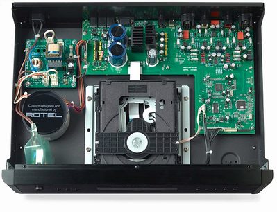 Rotel RCD-1572 sidabrinės spalvos CD grotuvas, vidinių elektroninių komponentų, žalių spausdintinių plokščių ir juodo ventiliatoriaus vaizdas