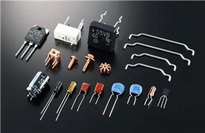 Diverse elektroniske komponenter: transistorer, kondensatorer, modstande og stik på en ensfarvet grå baggrund