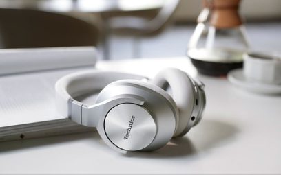 Навушники Technics EAH-A800 сріблястого кольору з відкритою акустикою, вид зліва, розташовані на білій поверхні, сріблясті навушники та дуга