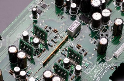 Circuit imprimé vert avec de nombreux composants électroniques, notamment des condensateurs cylindriques argentés