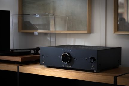 Чорний металевий підсилювач Onkyo, тричвертного ракурсу, з великим центральним регулятором, роз’ємом для навушників і органами керування праворуч