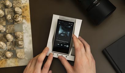 Przedwzmacniacz słuchawkowy Astell&Kern ACRO CA1000 trzymany w dwóch rękach na broszurze prezentującej urządzenie i złote elementy