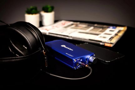 Amplificatore per cuffie audio blu Douk Audio con cuffie nere e smartphone su una scrivania