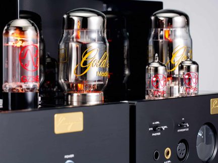 Valvole elettroniche in vetro, bagliore arancione, marcature rosse e gialle, su amplificatore in metallo nero, primo piano