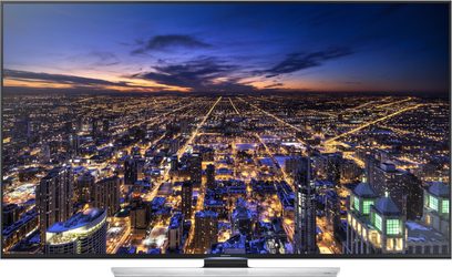 Samsung UE85HU7500-fjernsyn, der viser et natligt luftfoto af en oplyst by med mange skyskrabere