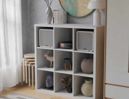 Black hi-fi system with a color display and two white speakers in a nine-compartment shelving unit
