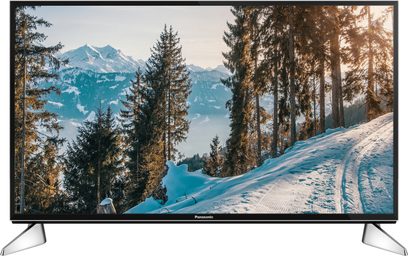 Panasonic TX-49EX600E-fladskærms-tv, der viser et snedækket bjerglandskab med grantræer under en blå himmel