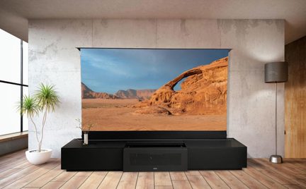 Siyah ultra kısa mesafeli lazer projeksiyon cihazı, modern bir salonda çöl manzarası gösteren büyük 4K ekran ile