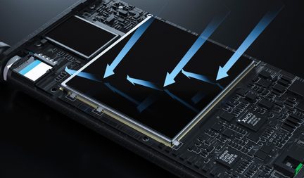 Primer plano oblicuo de una placa de circuito impreso negra de resina, con una amplia superficie rectangular brillante enmarcada por un contorno metálico plateado hacia la que convergen varias flechas azules translúcidas, rodeada de microcomponentes