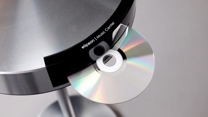 CD grotuvas su integruotu CD leistuvu, juodos ir sidabrinės spalvos, priekinė disko su blizgančiu paviršiumi įdėto į grotuvą stambaus plano nuotrauka