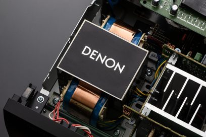 Innenansicht eines schwarzen Denon AVC-X3800H-Verstärkers, der die elektronischen Komponenten, Transformatoren und Verkabelung auf dem Chassis zeigt