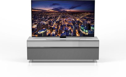 Gråt TV-møbel med fladskærm, der viser et natligt luftfoto af en stor, oplyst storby med tætliggende højhuse