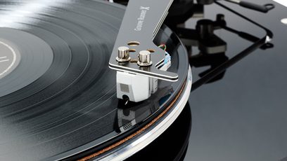 Nærbillede oppefra af den sorte Groove Runner X tonearm med aluminiumshoved, den sølvfarvede pickup og den sorte pladetallerken med metalrand, der bærer en vinylplade, hi-fi pladespiller Vertere Acoustics Pack DGX Sabre Lite sort med blank akrylfinish