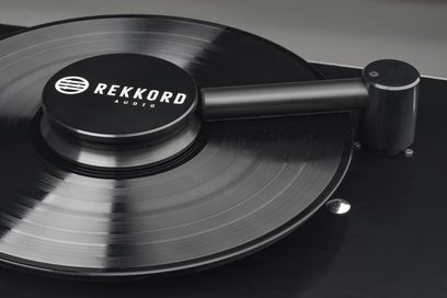 Vinylová deska Rekkord Audio RCM, detailní pohled shora, raménko a kruhový kovový otočný talíř s kartáčovaným povrchem
