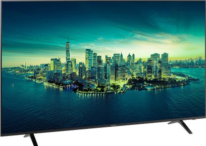 Panasonic TX-75LX700E-fladskærm, der viser et natligt luftfoto af en oplyst by ved vandet