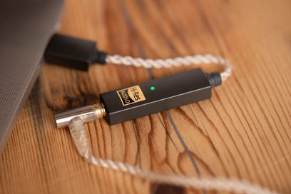 Draagbare iFi Audio GO Link zwarte audio-omvormer, aangesloten op een gevlochten witte kabel, close-up vooraanzicht