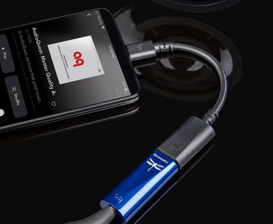 Smartphone nero visto dall'alto, cavo USB collegato a un adattatore audio blu in alluminio con logo a forma di libellula
