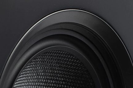 Vista ravvicinata di un altoparlante nero con una texture in fibra di carbonio e contorni circolari